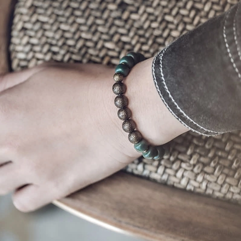 Side view of Tibetan bodhi seed copper bracelet on wrist, showing alternating bronze and dark green bead pattern with casual styling