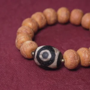Close-up side view of bodhi seed dzi bead bracelet showing textured beads and black-white three-eyed dzi pattern detail