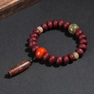 Overhead flat lay view of bodhi seed dzi bead mala bracelet with long dzi bead pendant on dark background