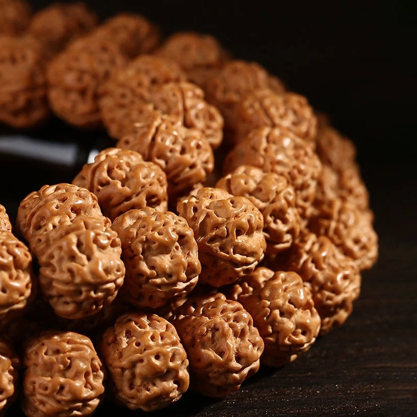 Bodhi seed and three-eye dzi bead mala materials close-up, showing natural stones used in traditional Tibetan spiritual jewelry