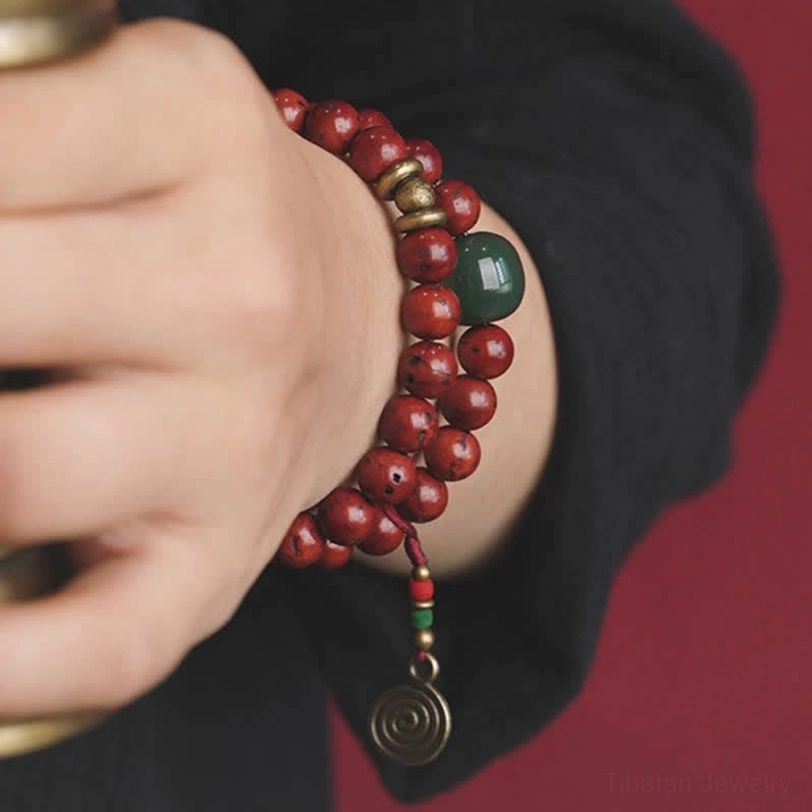 Cyan jade bodhi seed bracelet on wrist with brass metal accents and traditional design details