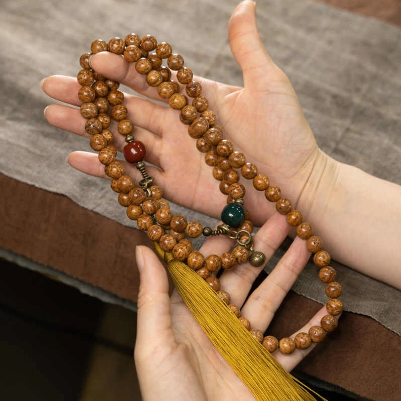 Bodhi seed mala bracelet held in hands showing natural beads and colored accents for meditation practice