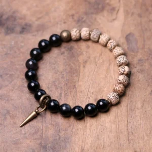 Tibetan Bodhi Seed and Black Obsidian protection bracelet featuring natural beads with brass spike pendant, displayed on wooden table from overhead view