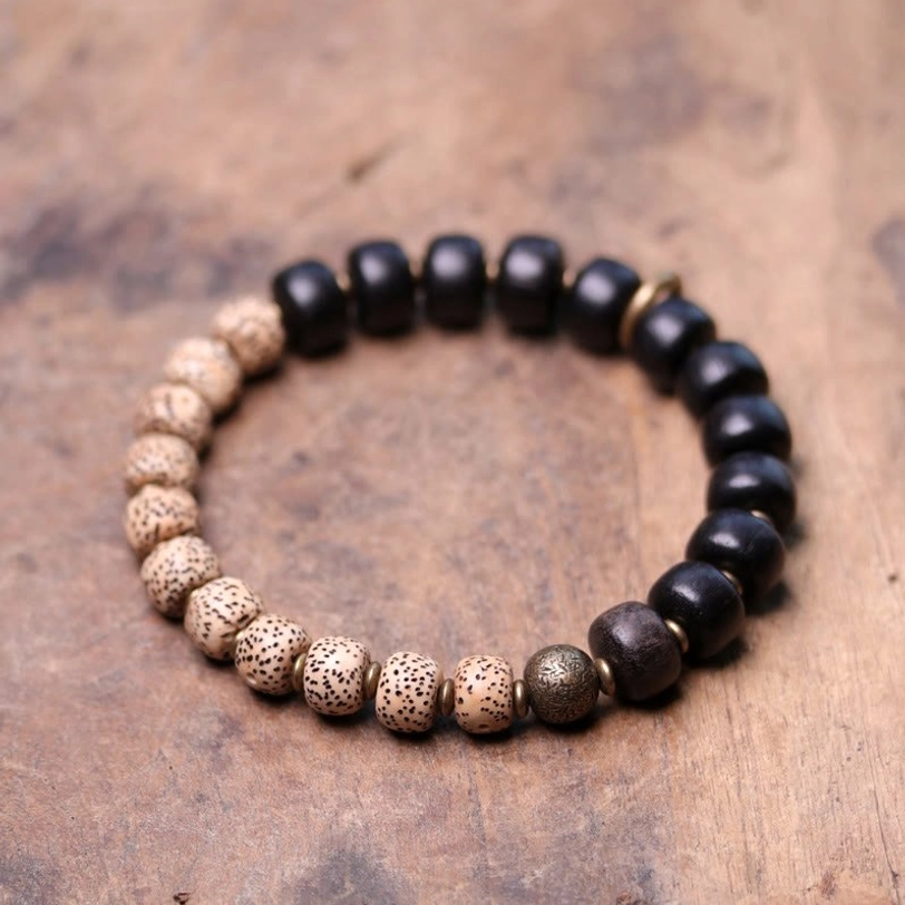 Stretch Tibetan Bodhi Seed and Black Obsidian bracelet flat lay on wooden tabletop showing alternating bead colors and brass hardware