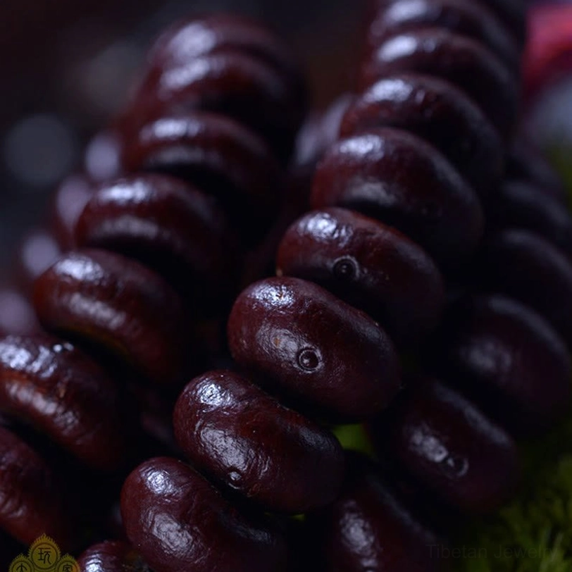 Macro close-up of Purple Bodhi Seed beads showing oval-flat texture and rich reddish-brown color detail