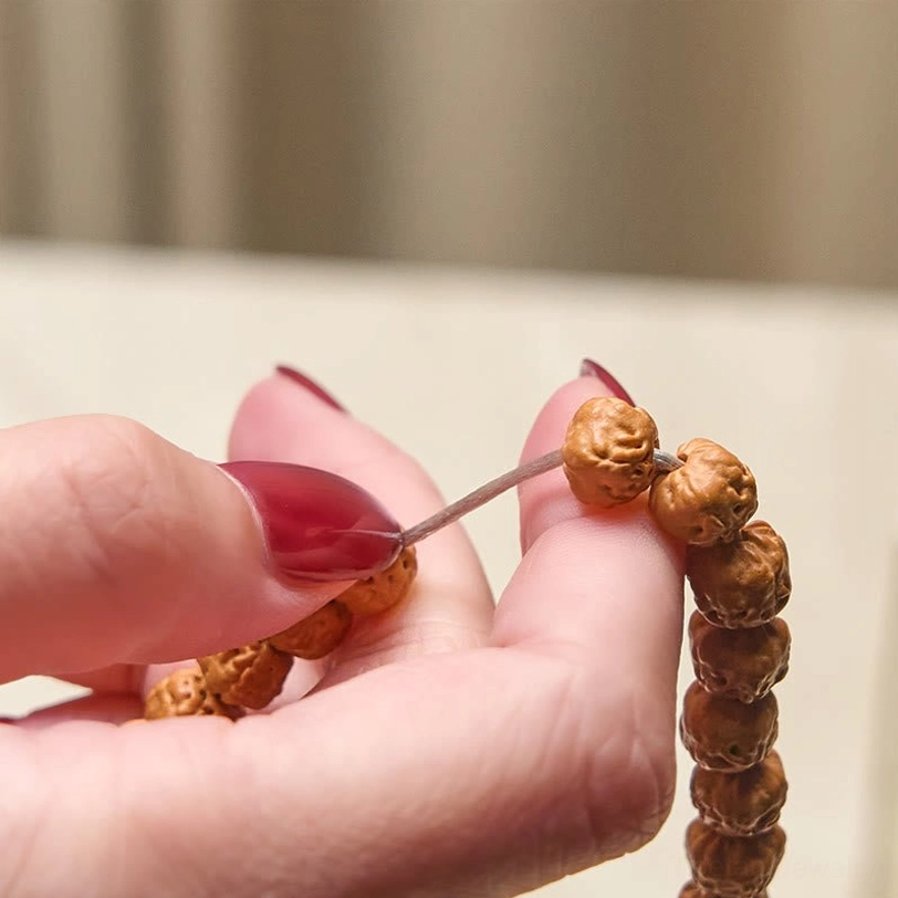 Close-up detailed view of bodhi prayer beads held in hands showing carved bead texture and natural surface