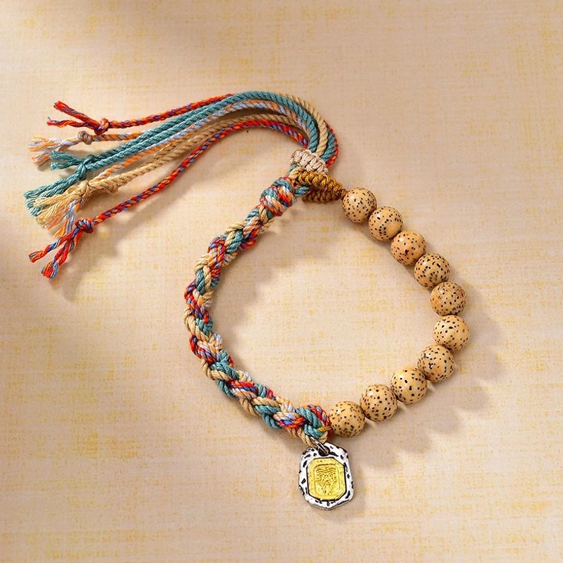 Close-up of Tibetan bodhi seed bracelet featuring full strand of speckled enlightened beads, multicolor cord, and rectangular Zakiram charm