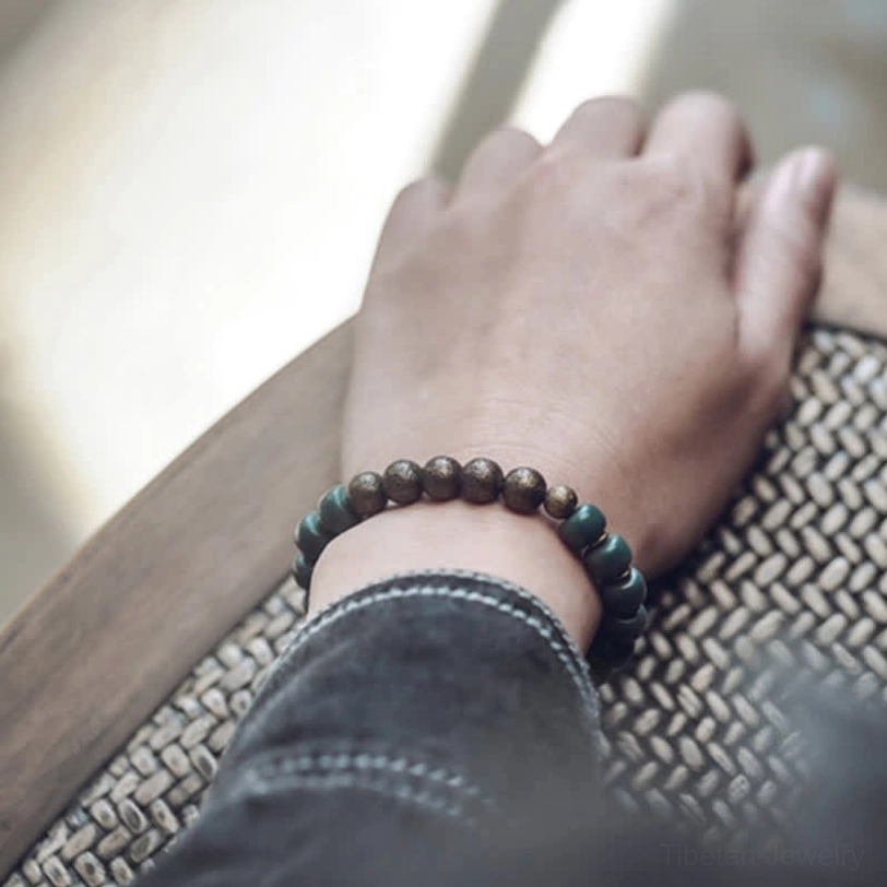 Back view of bodhi seed copper bracelet worn on wrist, highlighting the bronze and dark green bead alternation with denim cuff