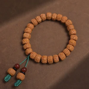 Top-down flat lay of bodhi seed prayer bracelet with cylindrical beads and tassel pendants on leather