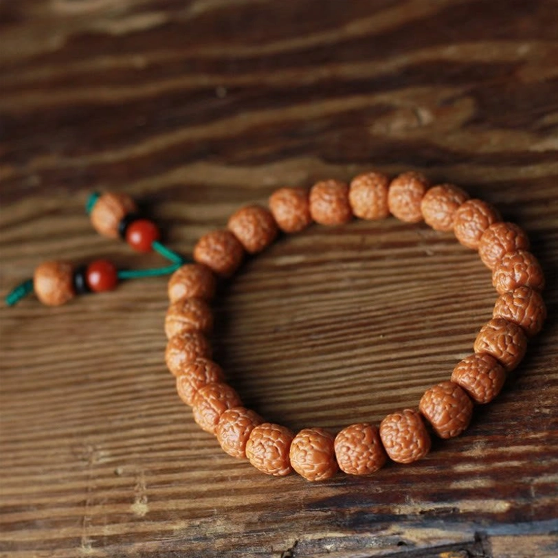Side flat lay view of complete bodhi seed bracelet loop with tassel and agate accent