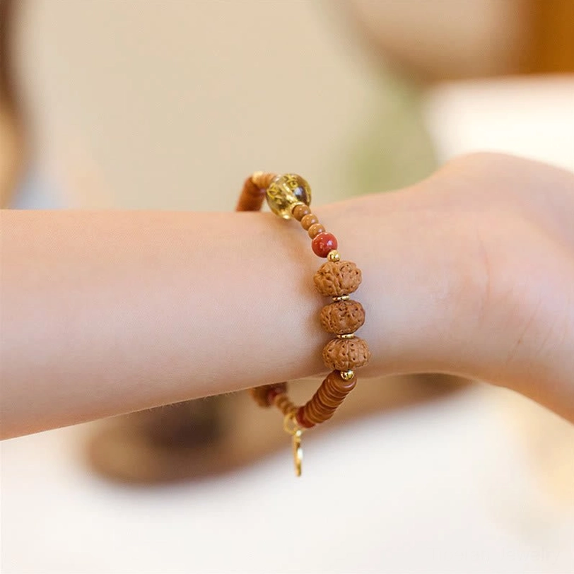 Bodhi seed beaded bracelet with dangling gold Fu charm, overhead handheld view