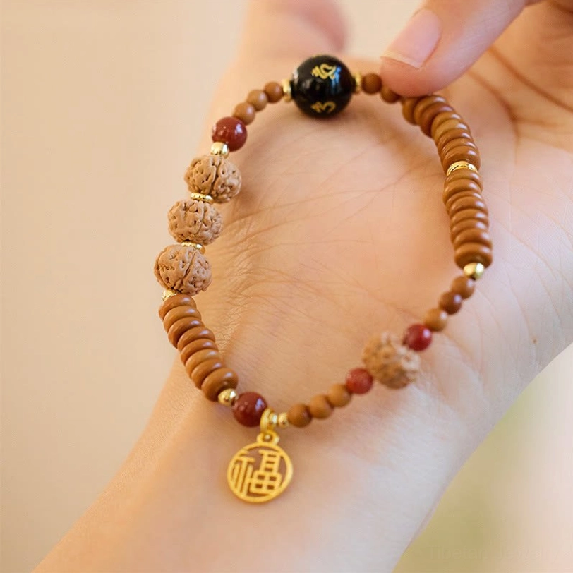 Bodhi seed beaded bracelet on palm, close-up showing gold Fu charm pendant and black onyx mantra bead