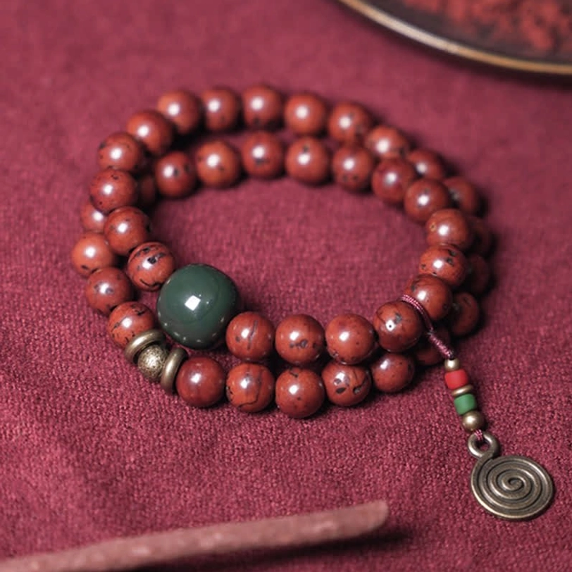 Single wrap bodhi seed bracelet with spiral metal pendant and incense stick styled photography