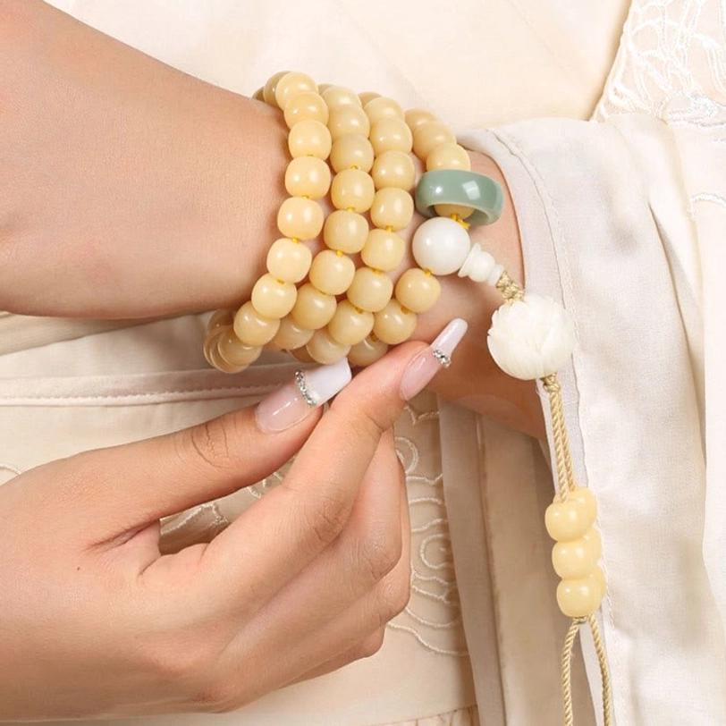 Stacked bodhi seed bracelets worn on wrist with white lotus charm and jade spacer visible