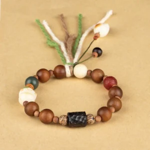 Handmade wooden beaded bracelet with multi-strand fabric tassel and flower decoration, top-down view on light beige background