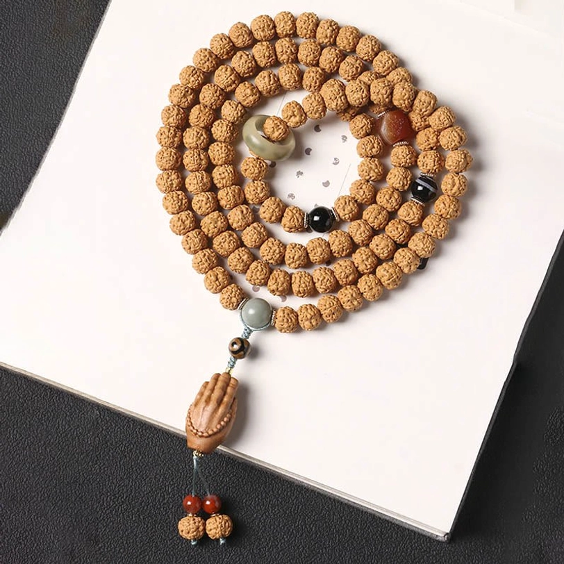 Coiled Bodhi seed bracelet with mixed decorative beads and three-eye Dzi bead on white background