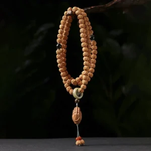 Coiled Bodhi seed prayer bracelet with three-eye Dzi bead and wooden Buddha hand charm pendant on dark green background