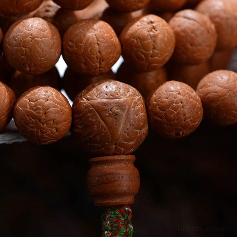 Macro photography of Bodhi seed mala beads showing thick brown seeds with distinct seed eyes and wooden guru bead with tassel