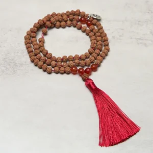 Tibetan 108 bodhi seed mala necklace flat lay with red tassel and Om charm on gray background