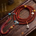 108 Bodhi seed mala bracelet overhead flat lay with turquoise accents, colorful tassel, and decorative elements on wooden surface
