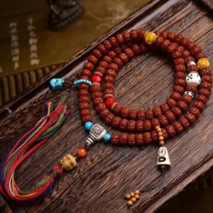 108 Bodhi seed mala bracelet overhead flat lay with turquoise accents, colorful tassel, and decorative elements on wooden surface