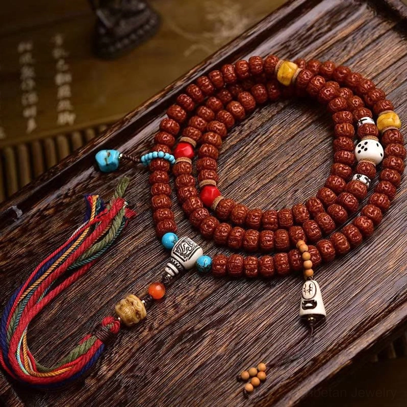 108 Bodhi seed mala bracelet overhead flat lay with turquoise accents, colorful tassel, and decorative elements on wooden surface