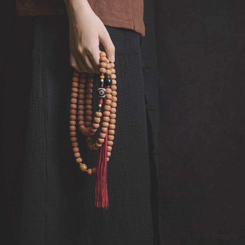 Bodhi seed mala bracelet handheld close-up showing individual bead texture and red tassel detail
