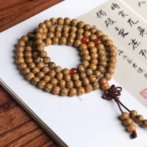Handmade 108-bead prayer mala with natural bodhi seeds, red agate spacers, and woven tassel on calligraphy paper background