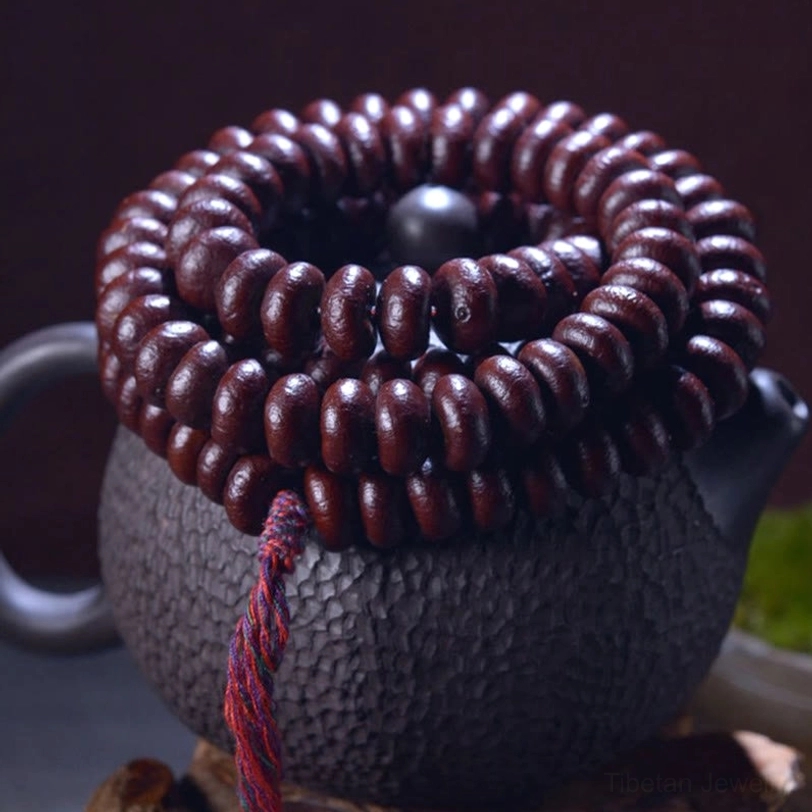 Close-up overhead view of 108 Purple Bodhi Seed mala beads bundled together on dark textured surface