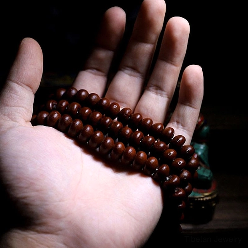 Tibetan mala prayer beads cluster on palm showing reddish-brown bodhi seeds and spiritual energy