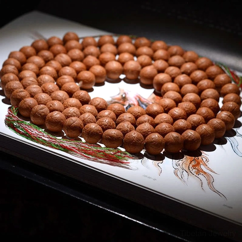 108 count Nepal Bodhi seed mala beads flat lay with multicolored woven tassel on spiritual book page