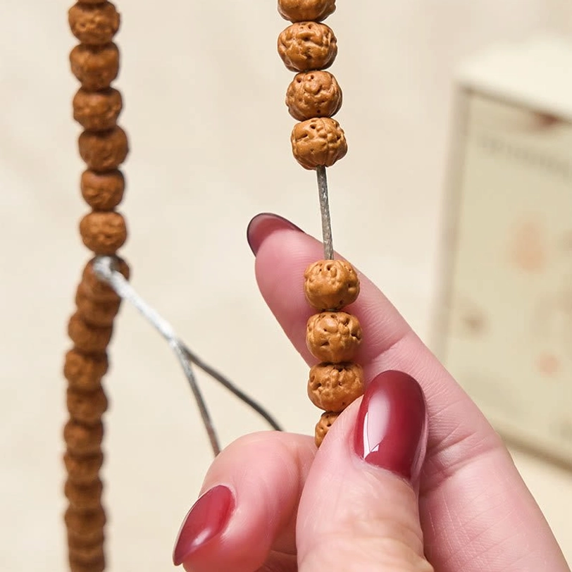 Two bodhi seed mala strands held side by side showing different bead sizes and carved texture comparison