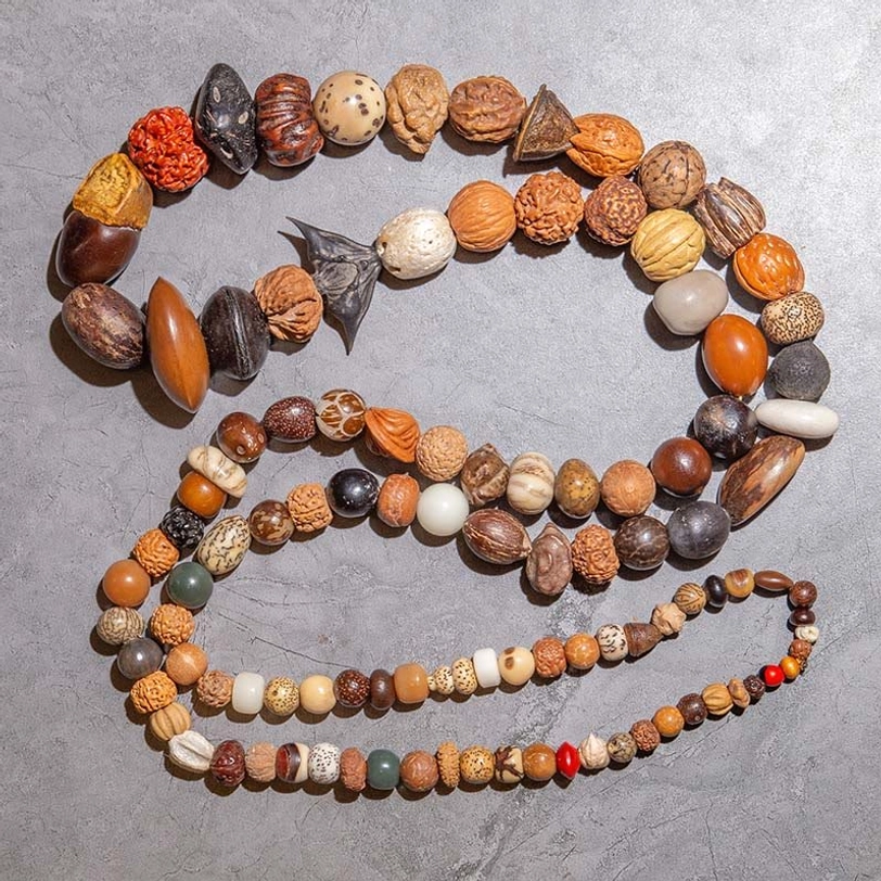 Two mixed Bodhi seed malas with red spacer beads and wooden decorative accents, flat lay showing natural seed textures