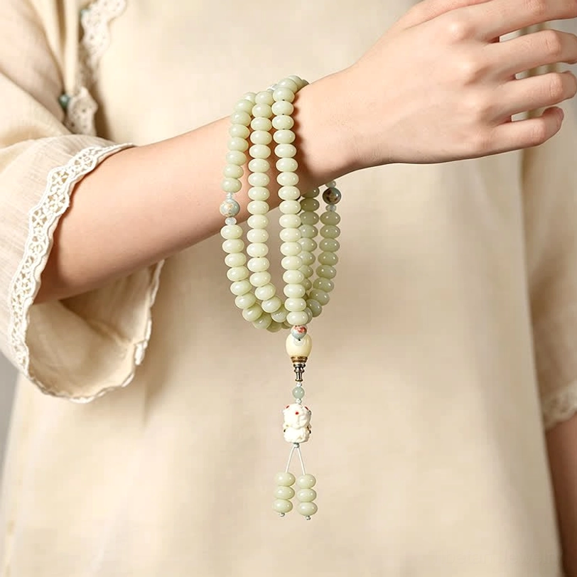 Tibetan bodhi seed mala bracelets worn stacked on human wrist with linen clothing backdrop