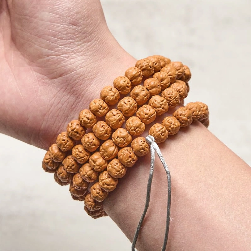 Tibetan bodhi seed mala worn on wrist as bracelet with multi-layered wrap and silver tassel accent