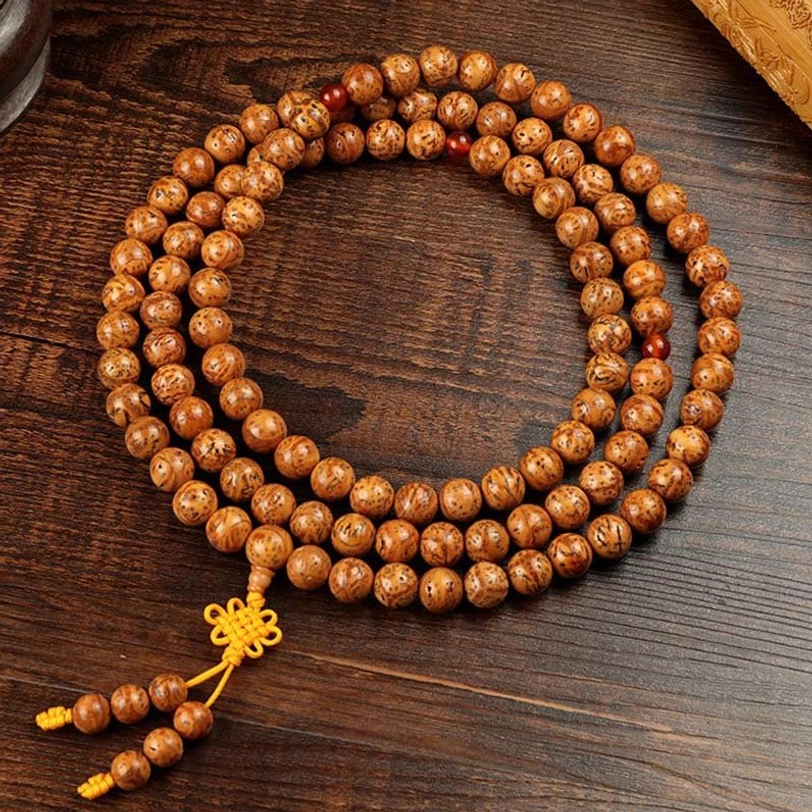 Full-length bodhi seed mala bracelet with 108 beads laid flat, showing complete strand with knotted yellow tassel and spacing pattern
