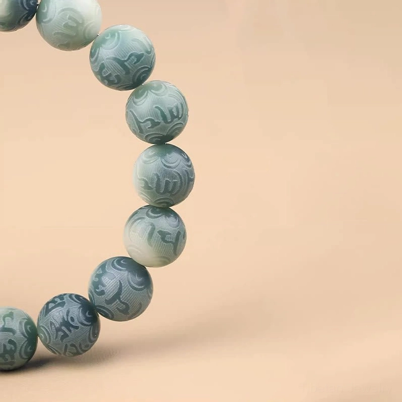 Close-up macro view of Om Mani Padme Hum engraved matte teal Bodhi seed beads on meditation bracelet