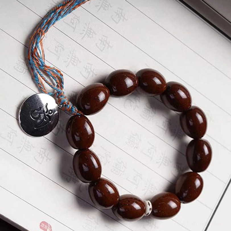 Lucky bodhi prayer bracelet with silver spacer beads and twisted blue-orange metal tassel pendant, flat lay view