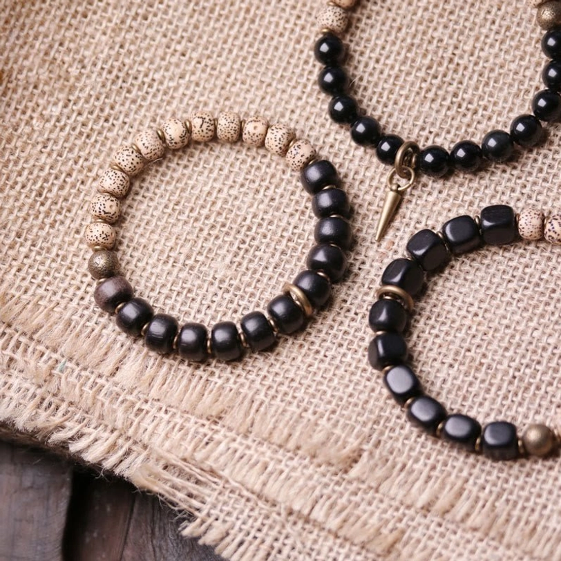 Trio of handmade Bodhi Seed bracelets with varied bead styles on burlap fabric over wooden surface