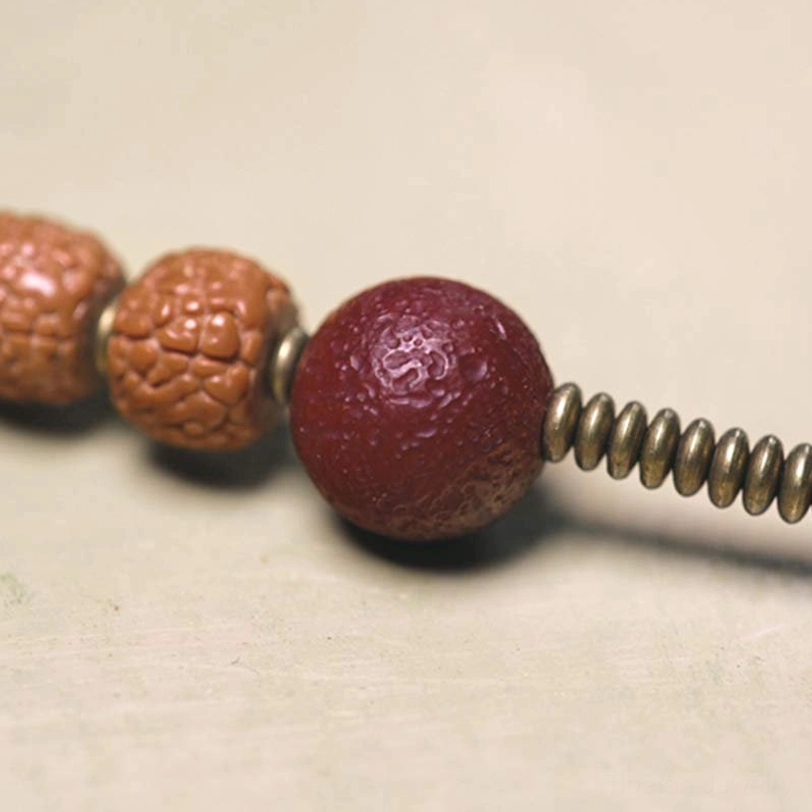 Detailed macro view of Rudraksha and Bodhi Seed beads with textured surfaces and red copper spacer bead accent