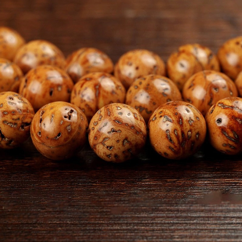 Close-up overhead view of natural bodhi seed beads showing rough pitted brown texture, uniform round shape, and authentic material detail