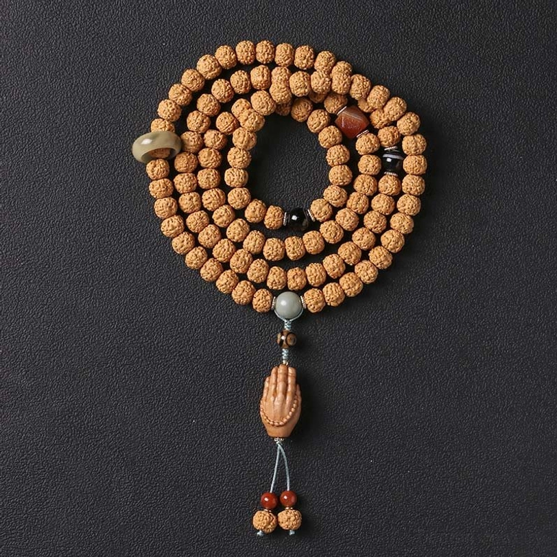 Bodhi seed mala bracelet with Dzi beads and wooden Buddha hand tassel pendant on black matte surface