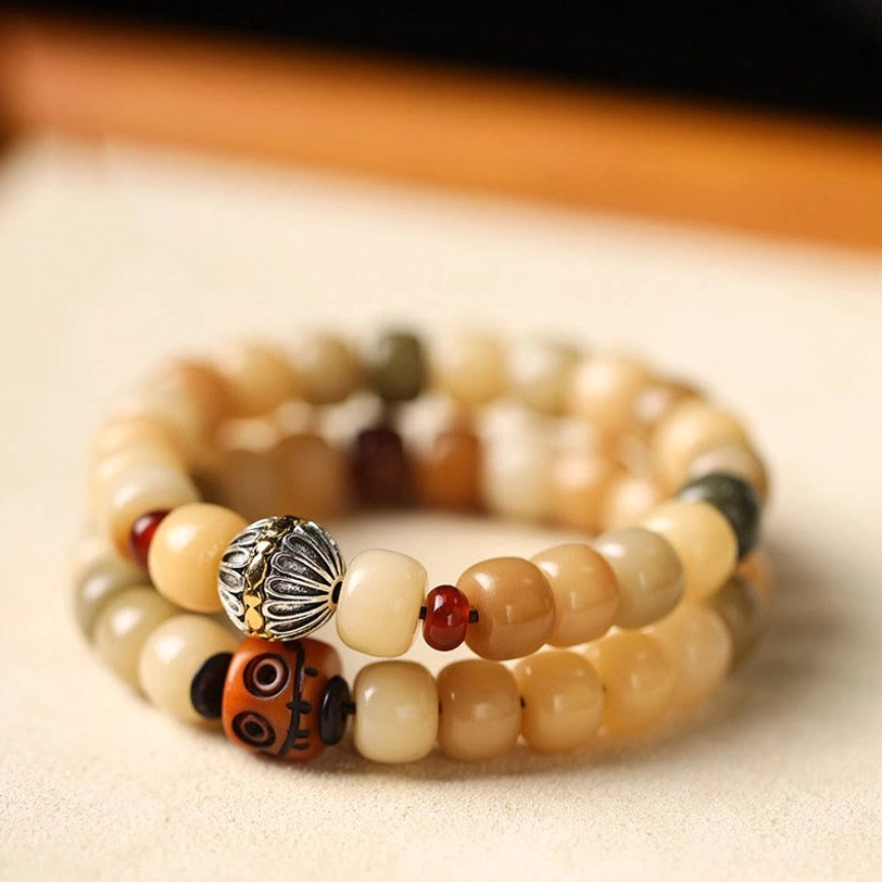 Bodhi seed wisdom bracelet with carved focal charm, close-up detail shot showcasing natural earth tone barrel beads and metal decorative elements