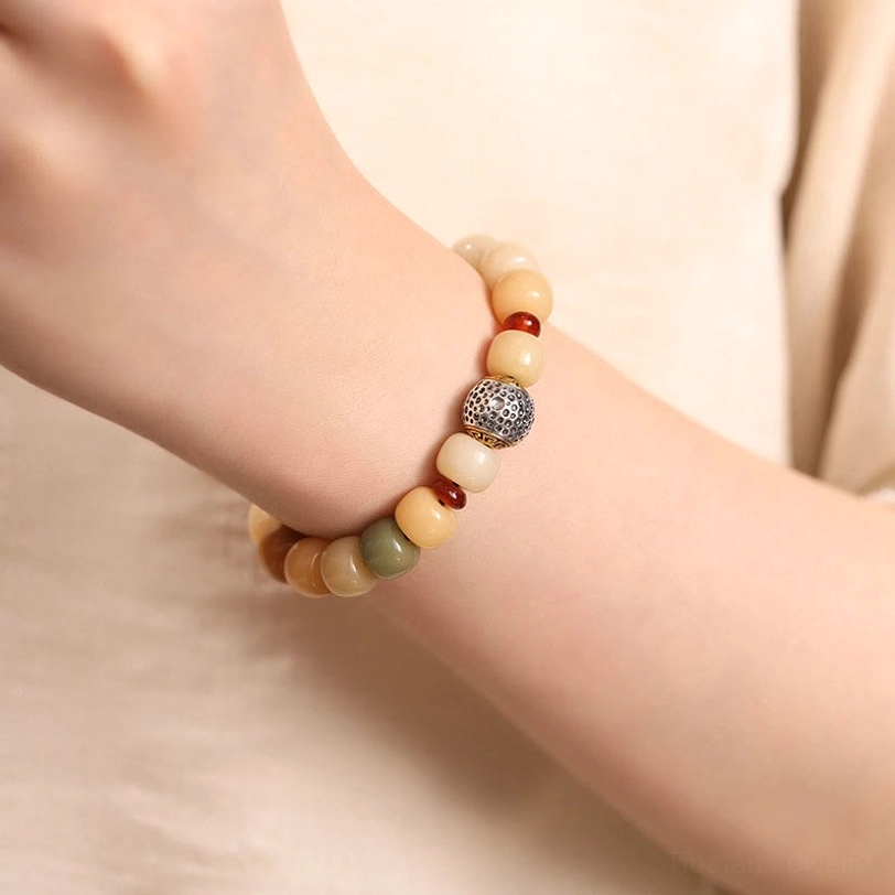 Bodhi seed spiritual bracelet worn on dual hands, close-up wrist view showing carved metal charm and earth tone beads in natural wear setting