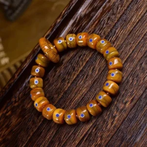 Close-up detail of cracked texture bone beads with blue lapis lazuli inlays on elastic Tibetan meditation bracelet against wooden background