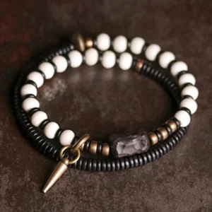 Matching pair of bone beads ebony wood bracelets with copper cone pendant displayed flat on leather background