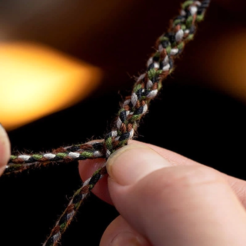 Close-up macro photograph of braided cord detail showing multi-strand woven technique and tight knot construction of Tibetan protection bracelet