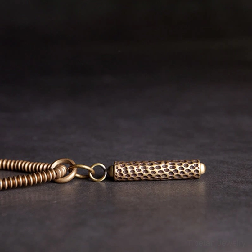 Vintage brass cylindrical pendant with textured coiled metal chain detail