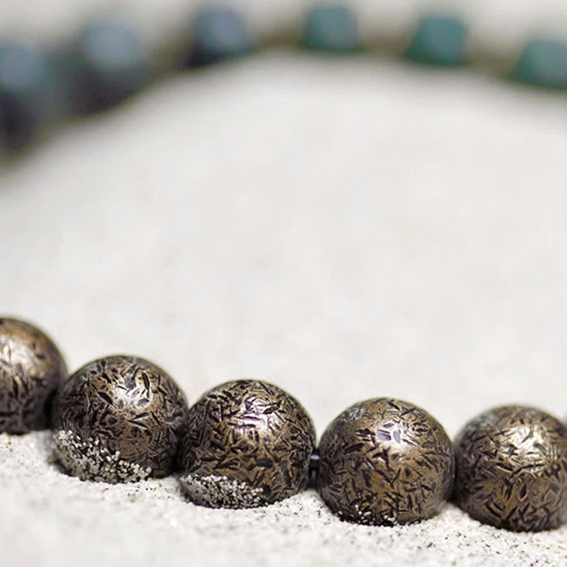 Macro photography of textured bronze metal spacer beads, showing detailed engraved surface and matte finish