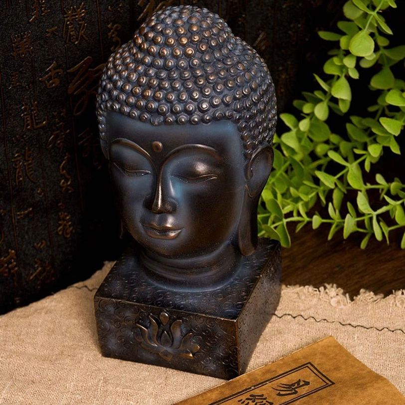 Bronze Buddha ornament with dark patina surface and lotus relief base, front direct view with calligraphy and foliage backdrop